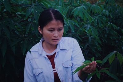 Young woman holding while standing by plants