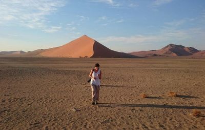 Mature woman walking on desert against sky