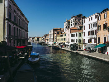 Canal amidst buildings in city against clear sky