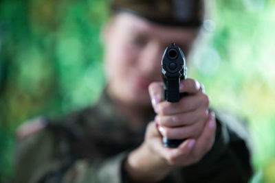 The lady soldier aims straight at the camera with a short gun.