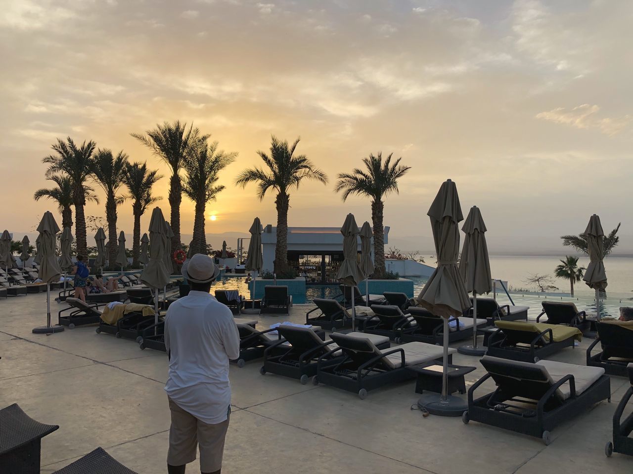 MEN STANDING AT BEACH AGAINST SKY DURING SUNSET