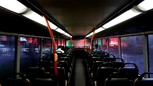 Rear view of man and woman sitting in bus at night