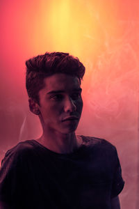 Portrait of teenage boy looking away against colored background