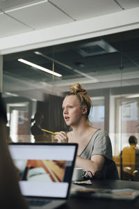 Businesswoman discussing with transgender colleague over laptop in board room during meeting