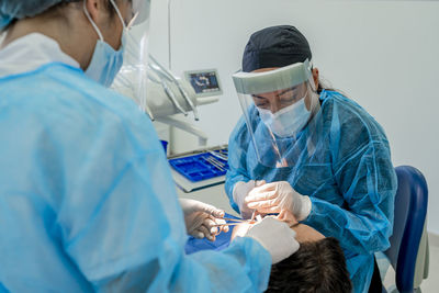 Surgeon with nurse doing surgery of patient in operating room at hospital