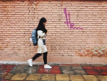 Full length of woman on brick wall