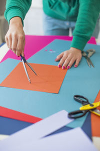 Cropped hands of woman with colorful papers on table