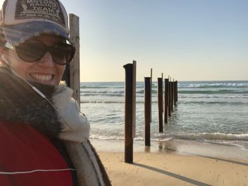 Portrait of smiling mid adult woman standing at beach against clear sky