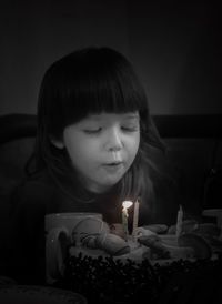 Close-up of girl blowing out birthday candles at home