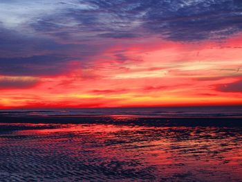 Scenic view of sea against dramatic sky during sunset