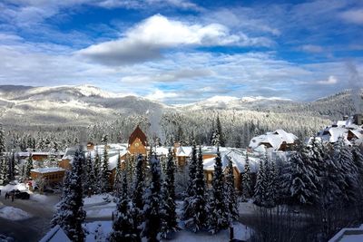 Snow covered houses by mountains against sky