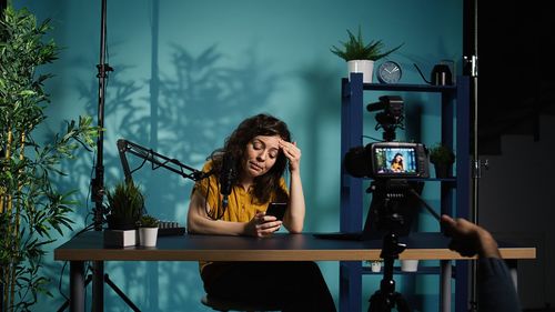 Young woman using mobile phone while sitting on table