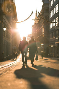 Rear view of people walking on road in city