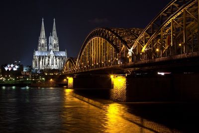 Illuminated hohenzollern bridge over rhine river against cologne cathedral