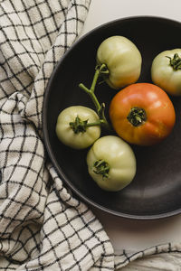 Homegrown green and orange tomatoes in a black bowl