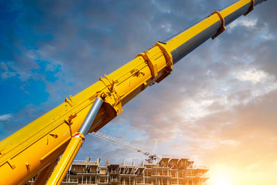 Low angle view of crane at construction site against sky