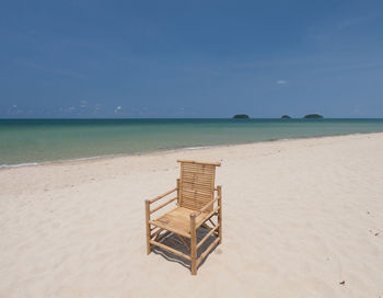 Deck chairs on beach against sky