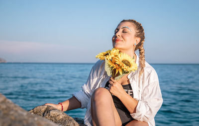 Beautiful young woman in sea against sky