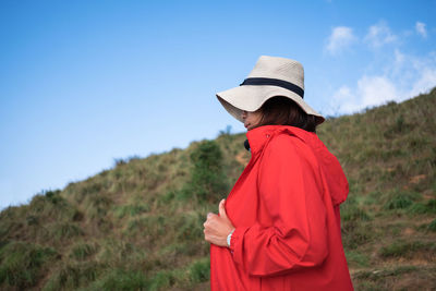 Side view of woman standing against blue sky