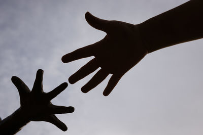 Low angle view of silhouette hand against sky