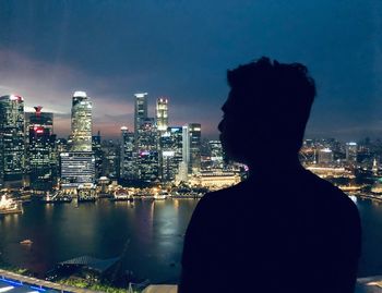 Silhouette man against illuminated cityscape at night