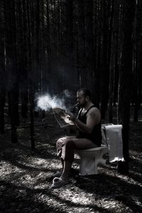 Young man sitting on seat in forest