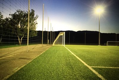 Illuminated light on soccer field against sky at dusk