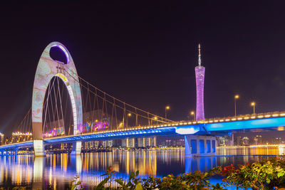 Illuminated bridge over river at night