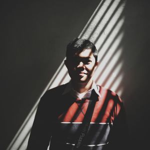 Portrait of young man looking away against wall