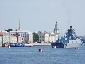 Sailboats in sea against buildings in city