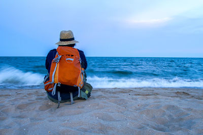 Rear view of hat on beach against sky