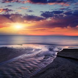 Scenic view of sea against dramatic sky during sunset