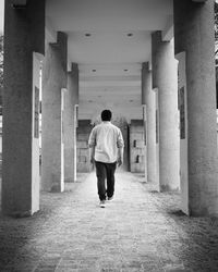 Rear view of man walking in corridor of building