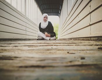 Portrait of woman in hijab sitting on footpath