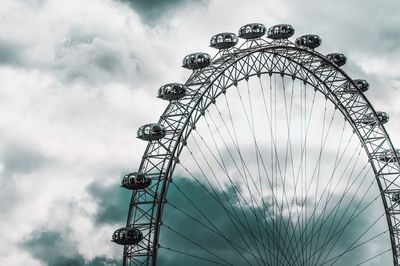 Low angle view of ferris wheel against cloudy sky