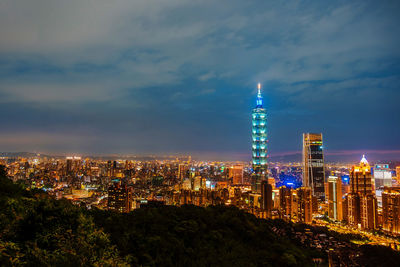 Illuminated buildings in city against sky at night