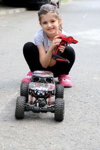 Portrait of girl playing with push scooter on road