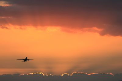 Low angle view of silhouette airplane flying during sunset