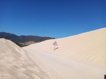 Scenic view of desert against clear blue sky