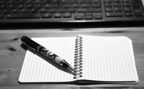 High angle view of pen over notepad on table
