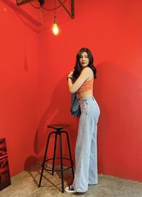 Young woman standing against yellow wall