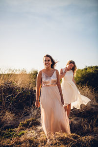 Young women standing against sky