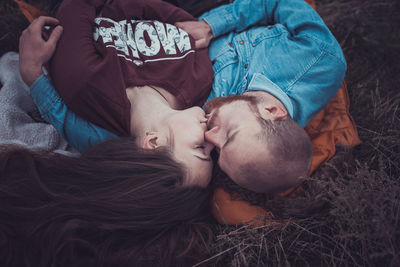 High angle view of couple kissing lying on grass outdoors