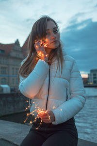 Close-up of young woman with burning hair against sky