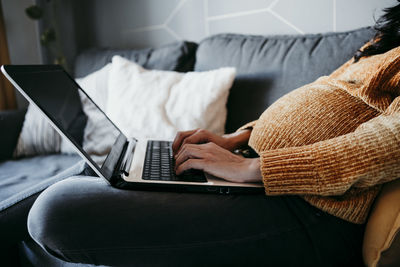 Pregnant woman using laptop at home