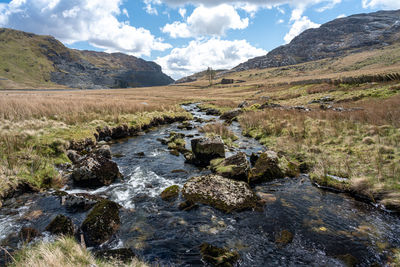 Stream flowing through rocks against sky