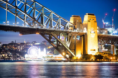 Illuminated bridge over river at night