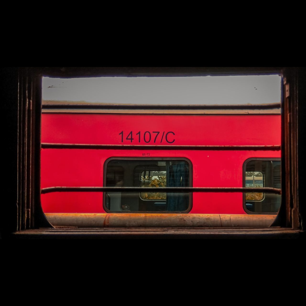 CLOSE-UP OF TRAIN ON RAILROAD STATION PLATFORM SEEN THROUGH WINDOW