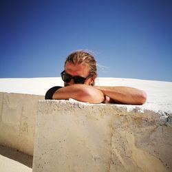 Young woman wearing sunglasses on desert against clear sky