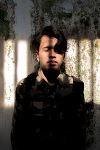 Portrait of young man standing against wall